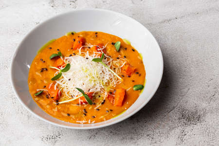 Pumpkin traditional soup with creamy silky texture, garnished with tomatoes and parmigiano. Marble background. copyspace. top view.の写真素材