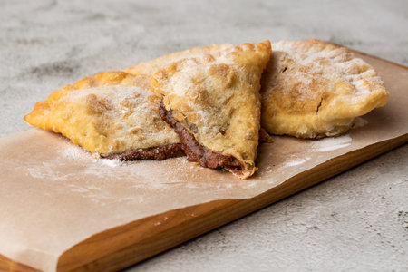 Uzbek eastern Tatar cuisine, sweet cheburek on a wooden board. Cheburek - fried pie with chocolate
