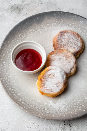 Cottage cheese pancakes, Syrniki or Cheesecakes with red sauce isolated on black marble background....