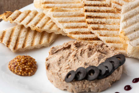 Liver meat pate spread with grilled white bread on a wooden background, breakfast, close-up, no people, selective focus, pasticcio, pastete.の写真素材