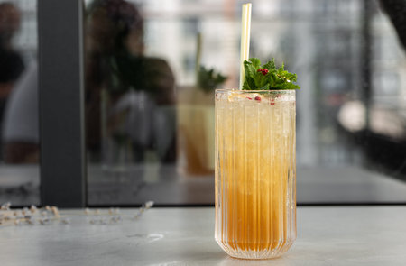 Glass with orange mojito cocktail with lemon and mint, cold refreshing drink or beverage with ice on...