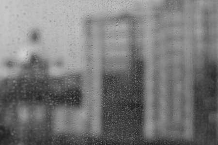 Large raindrops on glass in focus, window, cable car in fog, one phonikuler blurred, out of focus. Rain drops on window glass surface with cloudy background . Natural Pattern of raindrops.の写真素材