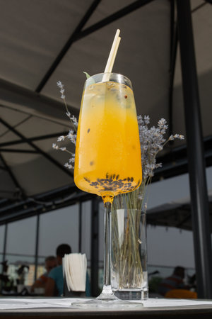 Glass with yellow lemon and passion fruit cocktail decorated with dried pineapple and mint on the bar on a bright backgroundの写真素材