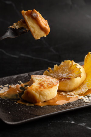 Hand with fork of Cottage cheese pancakes. Syrniki or Cheesecakes with dried pineapple and caramel...
