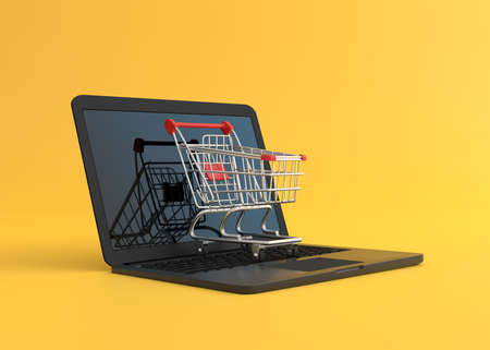 Shopping cart over a laptop computer, isolated on yellow background. Shopping Trolley. Grocery push cart. Online shopping and advertising concept. 3d render illustrationの写真素材