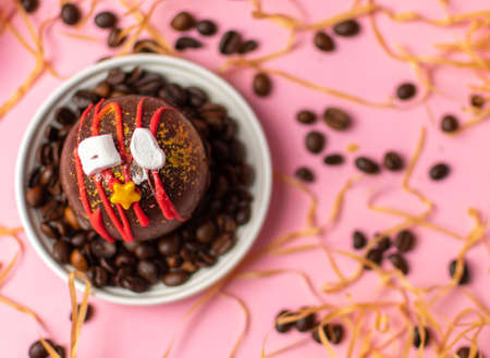 a chocolate milk ball lies on a white plate with whole coffee beans scattered on a blurred pink background. View from above. High quality photoの写真素材
