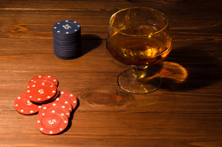 Playing cards and wine glass of cognac on wood table. Cognac drinks on wood background