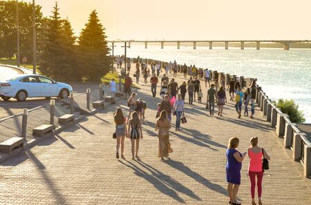 A crowd of anonymous people walking along the busy city waterfront. Sunny evening of the day off on the busy city waterfront of the Dnieper, Ukraine.のeditorial素材