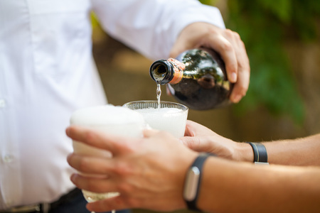 Man pouring champagne into glasses outdoorの写真素材
