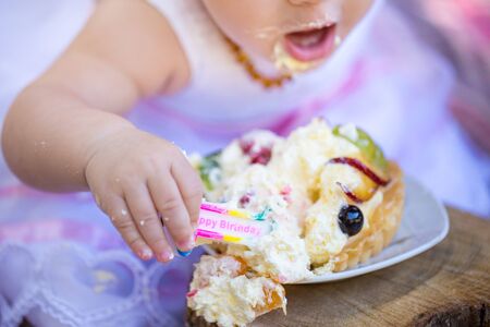 Baby girl eating her fist cake on her birthdayの写真素材