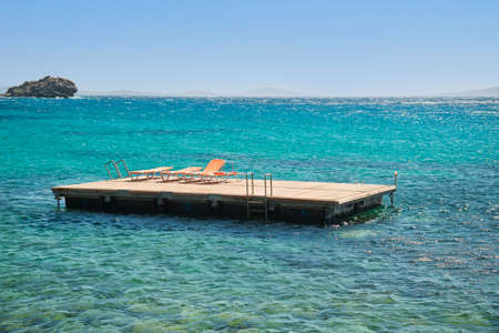 Sun beds in the water at Santorini island . Aegean sea , Greece .Magnificent view. Famous travel destinationの写真素材