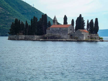 Castle on an island in the sea, against a background of mountains and blue skyの写真素材
