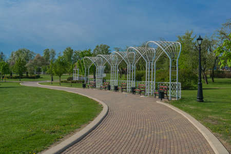 paths in a spring park landscape against a blue sky and green treesの写真素材
