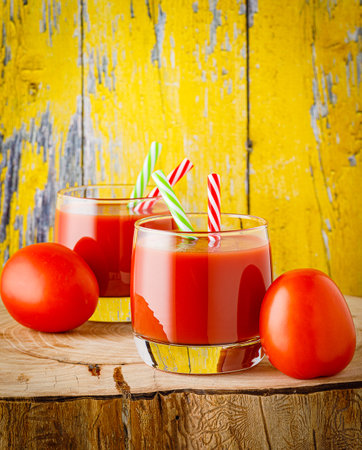 Glass of tomato juice and fresh tomatoes on wooden backgroundの写真素材