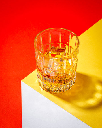 glass of whiskey on ice on the multi color backgroundの写真素材