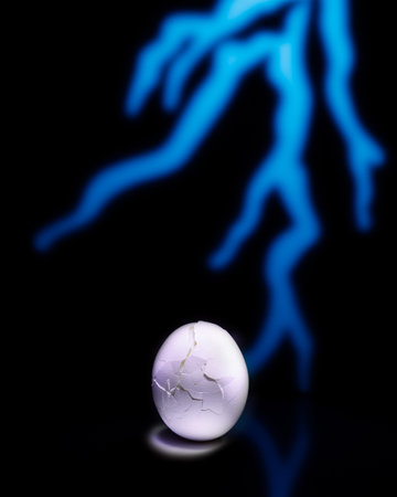 cracked boiled white egg and thunderbolt on black backroundの写真素材