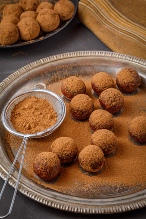 chocolate truffles or energy protein balls made with dry dates, walnuts, raisins, covered by cocoa powderの写真素材