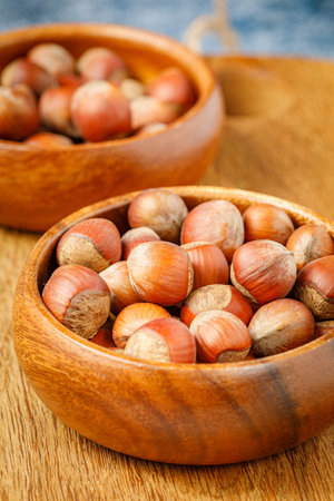 still life with hazelnuts in wooden bowles and on wooden board