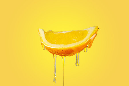 honey dripping slice of lemon on yellow backgroundの写真素材