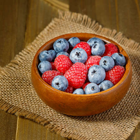 fresh blueberries and raspberries in wooden bowl aside with milk and yogurtの写真素材