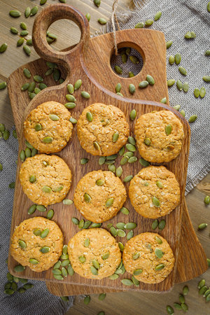 Fresh baked homemade oatmeal cookies with raisins and sunflower seeds on wooden background