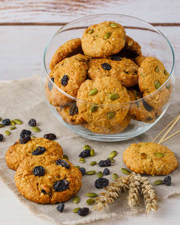 Fresh baked homemade oatmeal cookies with raisins and sunflower seeds on wooden backgroundの写真素材