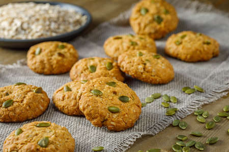 Fresh baked homemade oatmeal cookies with raisins and sunflower seeds on wooden backgroundの写真素材