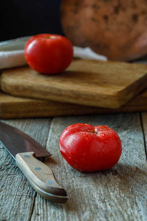 fresh tomatoes and knife on a chopping boardの写真素材
