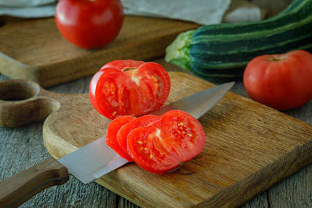 fresh tomatoes and knife on a chopping boardの写真素材