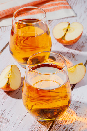 glass of apple juice and sliced apples on a tableの写真素材