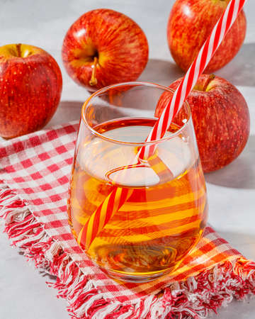 glass of apple juice and sliced apples on a tableの写真素材