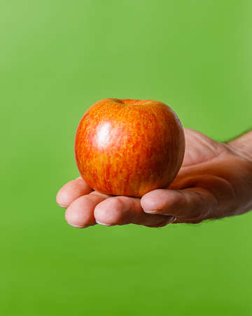 still life with hand holding an apple on green backgroundの写真素材