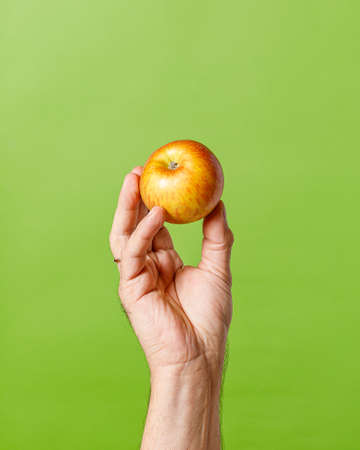 still life with hand holding an apple on green backgroundの写真素材