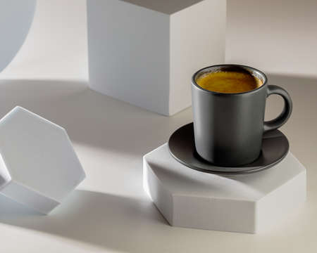Coffee in black cup on with cubical props and lighting backgroundの写真素材