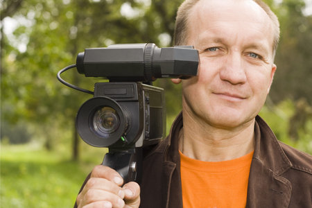 a grown man posing with a video camera on his shoulder 