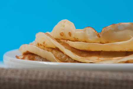 Pancakes on white plate. Blue background. Selective focus.