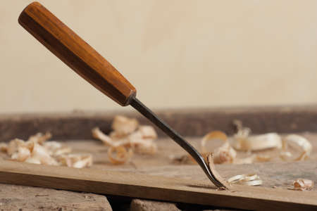 Chisel and wood shavings on a wooden workbench.の写真素材