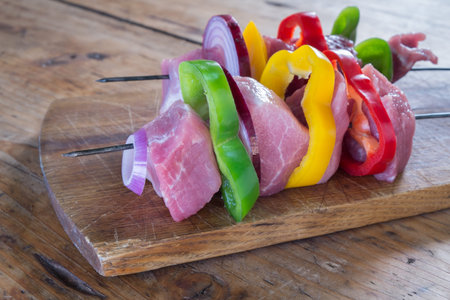 Raw pork skewers and vegetables on a wooden board. close upの写真素材