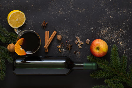 Christmas Mulled wine recipe ingredients on black. Bottle of wine, orange, apple, lemon, cinnamon sticks, anise, nutmeg, cloves and sugar from above. With text spaceの写真素材