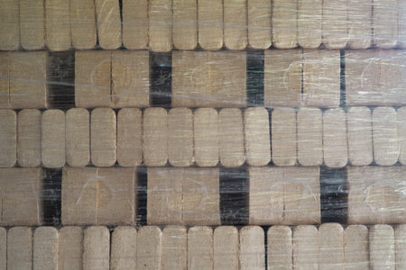 Pressed pine wood briquettes on pallets. Solid fuel for stoves from softwood shavings.