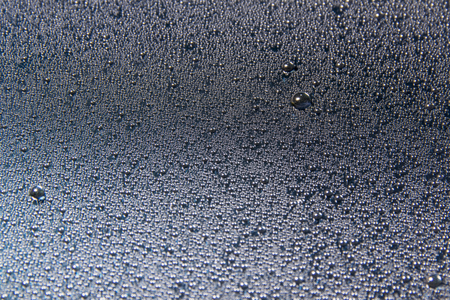 Water drops on glass glisten on black background, closeup textureの写真素材