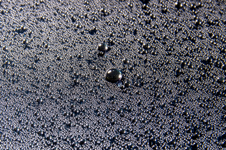 Water drops on glass glisten on black background, closeup textureの写真素材