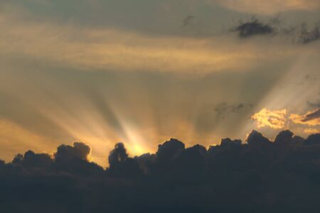 gray Cumulus clouds in a blue sky with orange lightの写真素材
