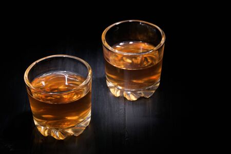 two glasses of cognac on a black treeの写真素材