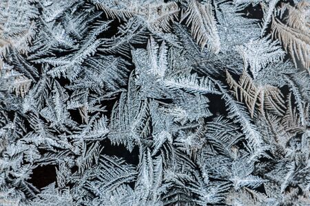 beautiful festive frosty pattern with white snowflakes on a blue background on glass seamlessの写真素材