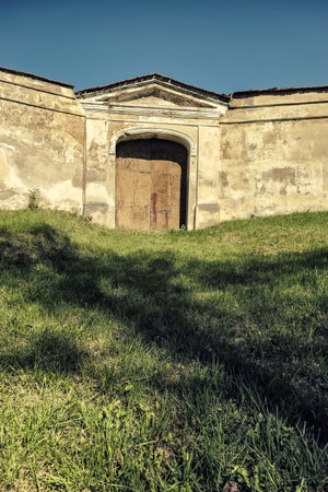 Monastery on the green hill with closed gate in a high wall
