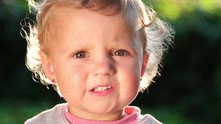 Beautiful face of a small European child, the sun illuminates her hair.