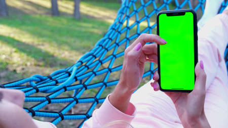Girl holding a smartphone with a chroma key screenの写真素材