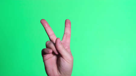 Two fingers up on the chromakey screen. Gesture of victoryの写真素材