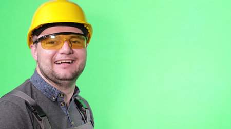 Portrait of engineer worker man on green background, laughing showing thumb up